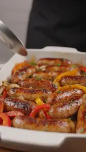 Baked sausage with colorful bell peppers in a serving dish