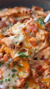 Cheesy pork enchilada bake topped with melted cheese and garnished for serving