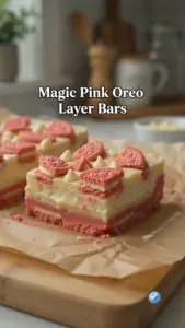 Magic Pink Oreo Layer Bars stacked on a white plate, showcasing their vibrant colors.