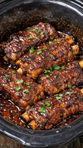 Delicious slow cooker BBQ beef ribs on a platter garnished with herbs.