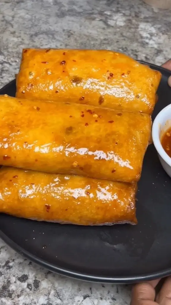 Delicious homemade crab rangoon rolls on a plate with dipping sauce.
