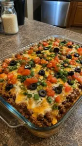 A delicious Loaded Taco Casserole topped with cheese, tomatoes, and jalapeños
