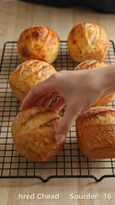 Cheddar cheese mini sourdough loaves on a wooden cutting board