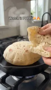 Freshly baked homemade pita bread served warm on a wooden board.
