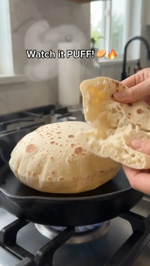 Freshly baked homemade pita bread served warm on a wooden board.