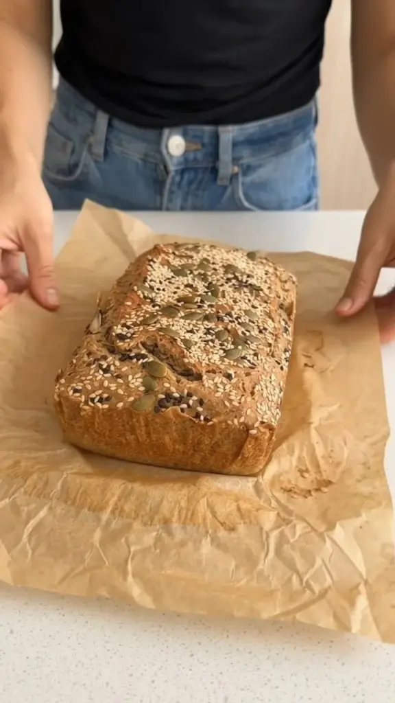 Freshly baked gluten-free buckwheat bread loaf on a wooden cutting board.